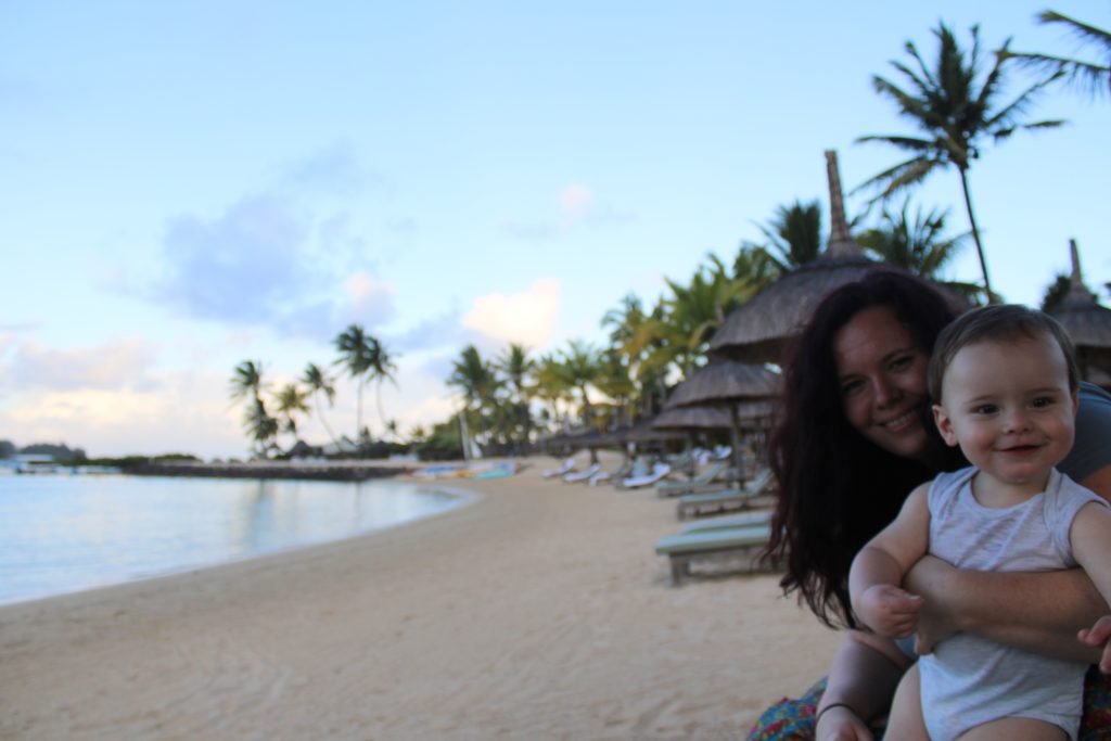 A woman and a baby on a beach chair enjoying a tropical island sunset.