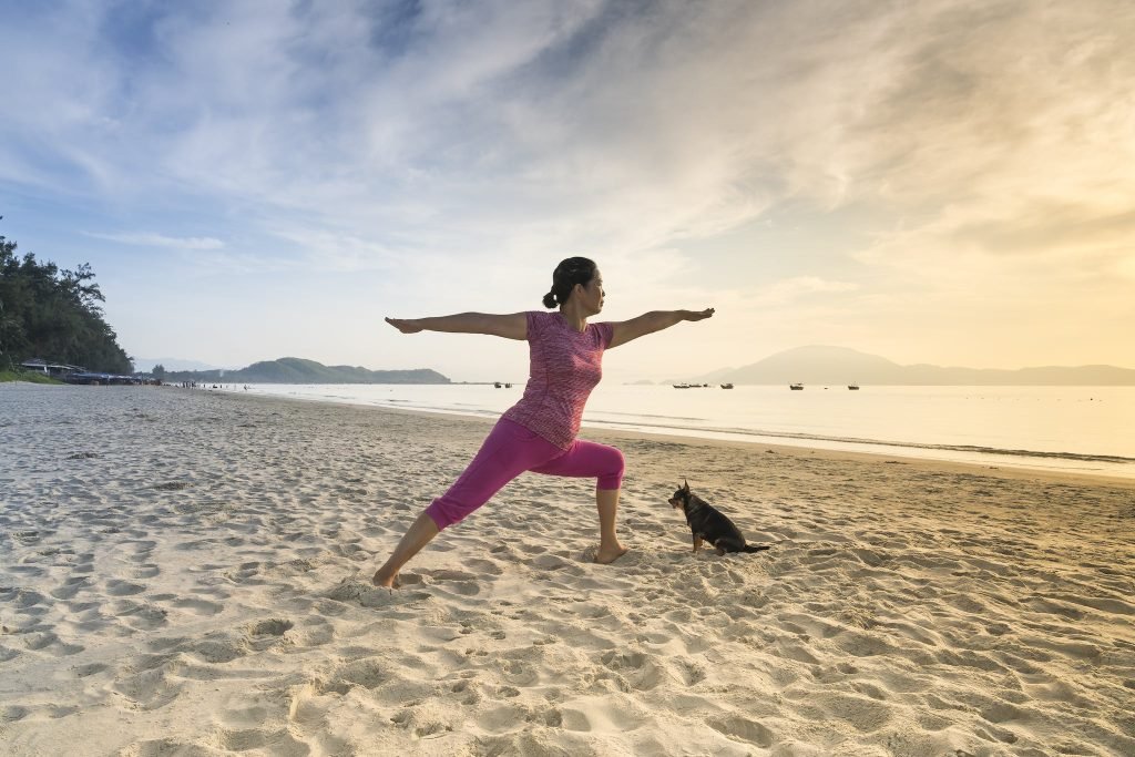 Woman In Pink Shirt Posing While Standing On Shore during one of these Christmas Yoga Retreats.