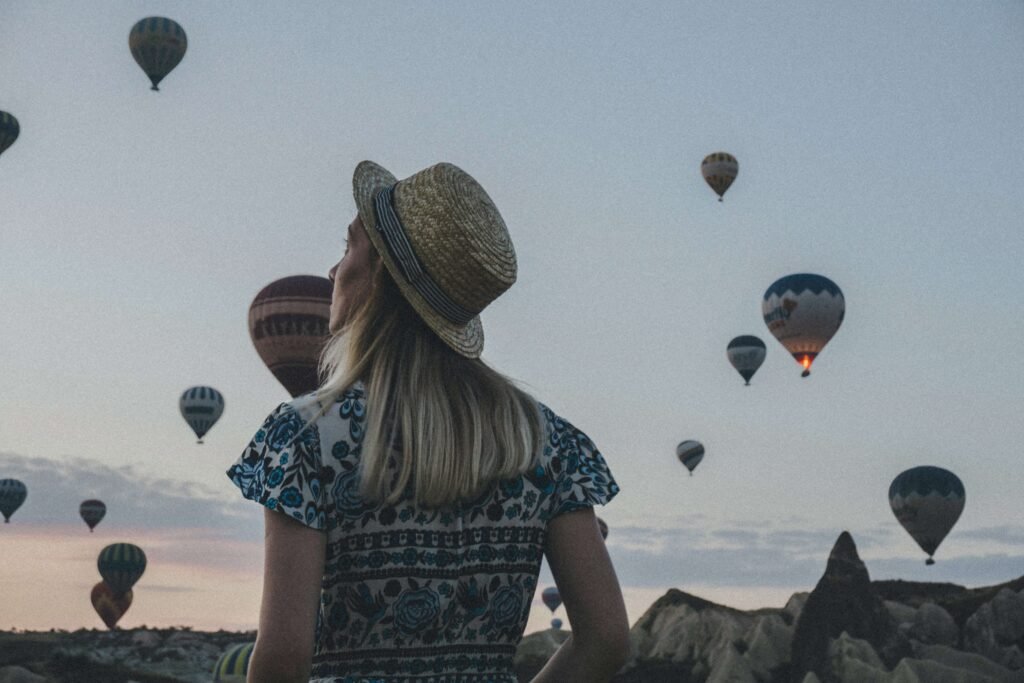 A woman watching the hot air balloons rise over Cappadocia which is a sight that many people have on their travel vision board.