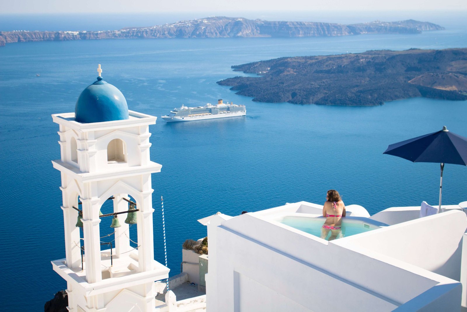A woman in a pool overlooking Santorini which is a common image for any travel vision board.