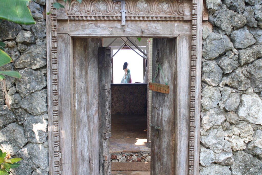 Carved wooden door that opens with a woman standing inside.