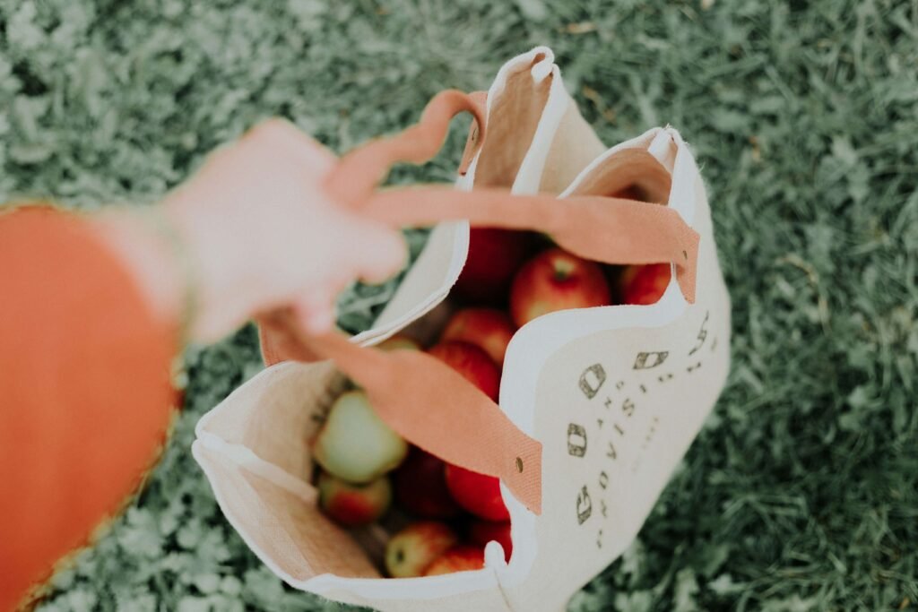 A woman carrying a reusable grocery bag full of fresh produce.