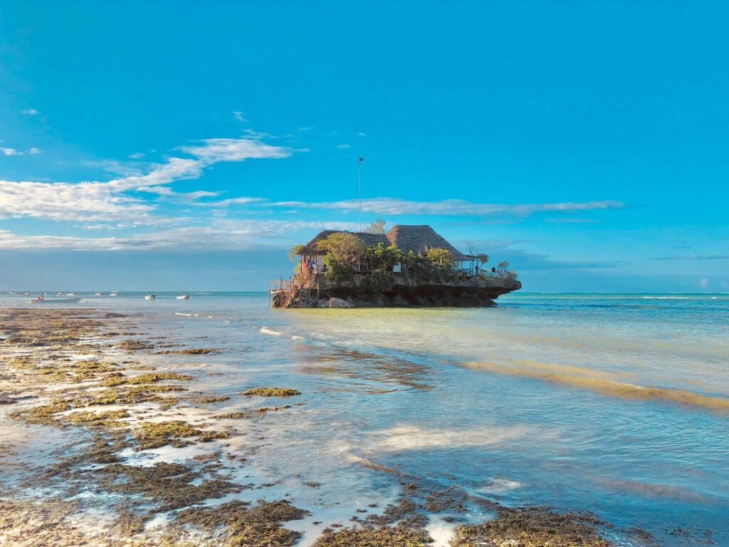 The Rock Restaurant in Zanzibar at low tide with boats in the distance.