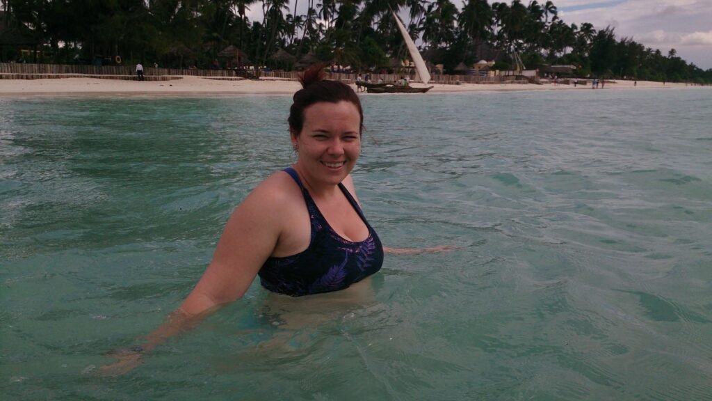 A woman swimming in the ocean at Jambiani Beach which is one of the best Zanzibar snorkeling spots.