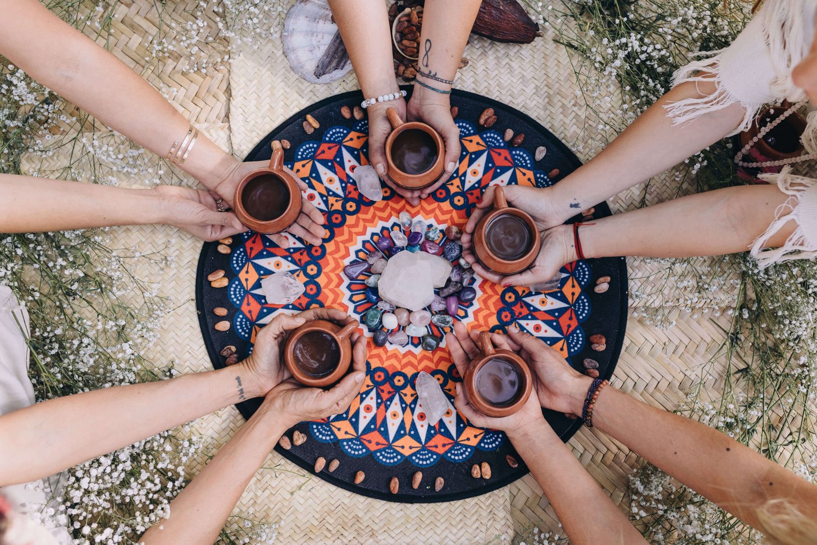 A group of women holding together their cups of cacoa during a cacao ceremony in show of sisterhood which is one of the benefits of retreats.