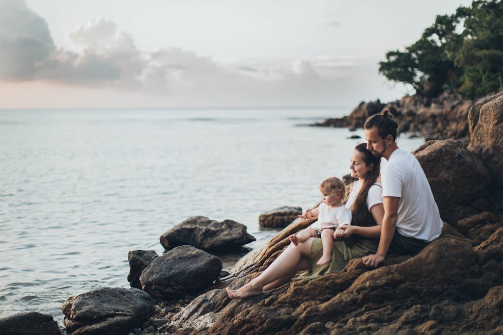 Man and Woman Sitting on Rock Near Seashore - family travel quotes.