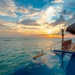 Woman enjoying a stunning sunset at a luxury Maldives resort's infinity pool.