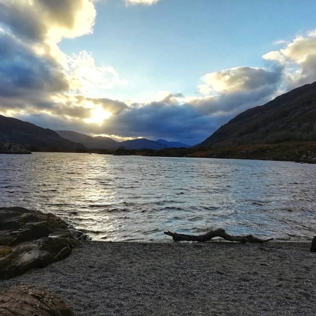 Sunset peeking through clouds over a peaceful loch in Ireland