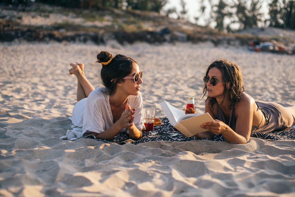 Two women enjoy a sunny day at the beach in Vietnam, reading and relaxing.